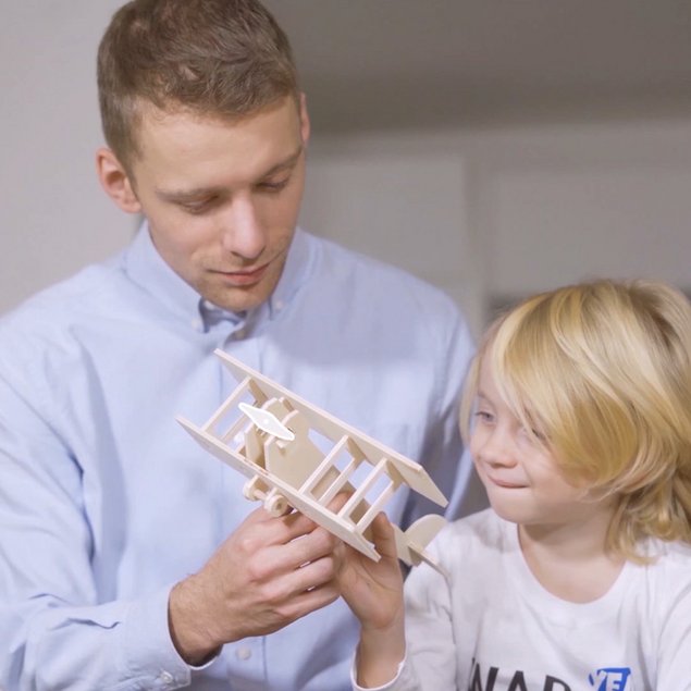 Kind und Vater spielen mit einem selbstgemachten Flugzeug aus Holz